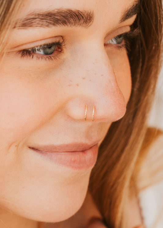 Close-up of a person wearing a Hello Adorn gold nose ring with a blurred background