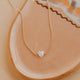 Gold necklace with a heart pendant on a ceramic plate
