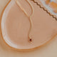 Gold necklace on a textured beige surface