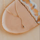 Gold necklace with a heart pendant on a beige dish