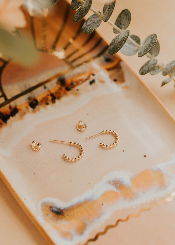 Gold earrings on a decorative tray with a soft focus background