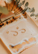 Gold earrings on a decorative tray with a soft focus background