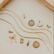 Gold necklaces with various pendants on a wooden surface