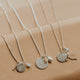 Silver necklaces with various pendants on a beige background