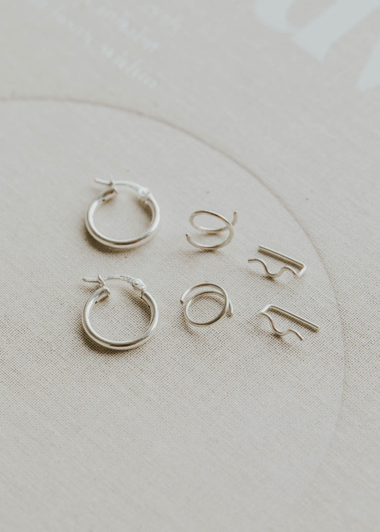 Set of silver hoop earrings on a light beige background