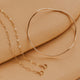 Gold bracelet and chain on a beige surface