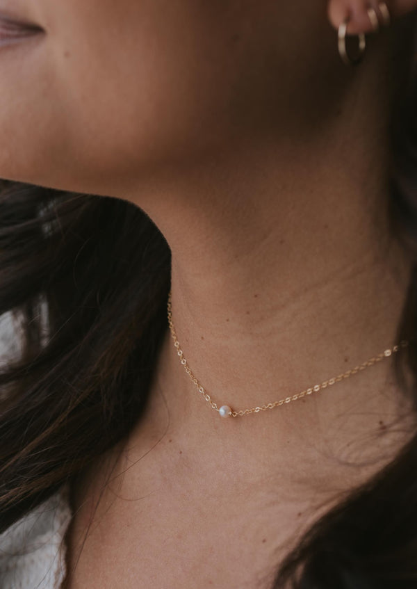 A freshwater pearl necklace handmade by Hello Adorn, a tiny freshwater pearl is attached to a delicate gold necklace chain creating this tiny pearl necklace.