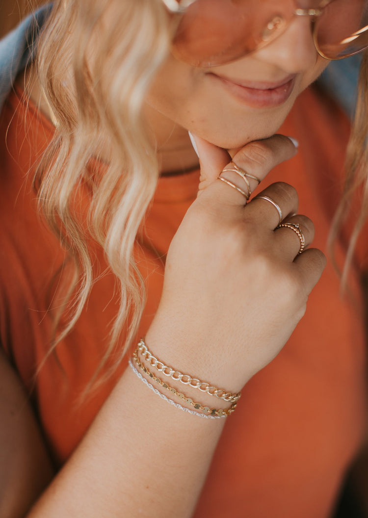 Wondering if you can mix gold and silver jewelry, the answer is YES! Hello adorn provides jewelry ideas for gold and silver jewelry together. this look features a ring stack which includes a cleo wire wrapped ring, two thin rings, a gemstone ring, and a beaded ring paired with a bracelet idea to create a bracelet stack with thick chain bracelets, a gold simple bracelet, and a simple silver chain.