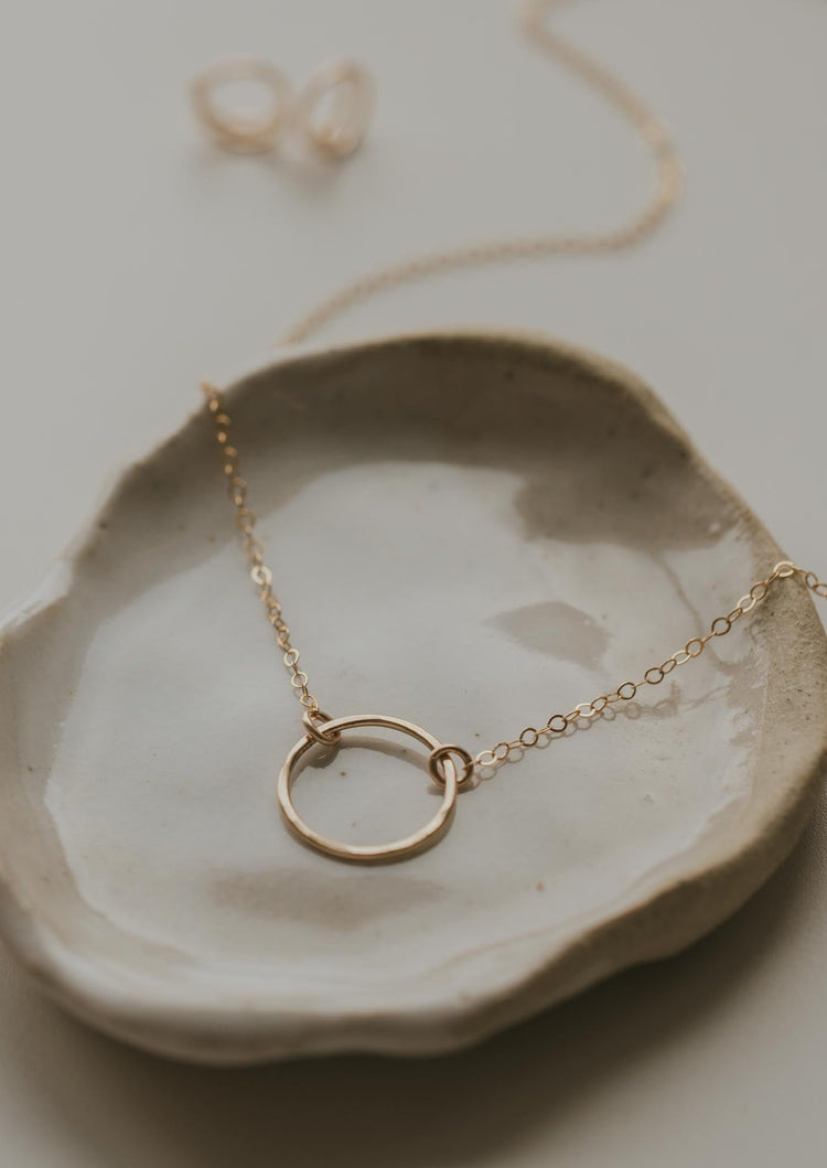 A charm necklace with a circle pendant handmade by Hello Adorn in the Full Circle Necklace design, a minimalistic necklace that can be worn as a statement necklace or add to a necklace layering look.