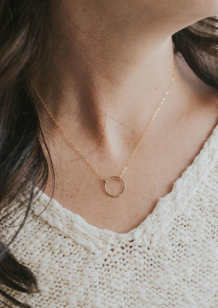 A model wearing the Full Circle Necklace handmade by Hello Adorn, a charm necklace with a circle pendant.