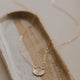 A close up look at the Supermoon Necklace from Hello Adorn, a necklace with a circle pendant hammered to make a moon necklace, a statement necklace to add to a necklace layering look.