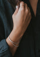 Mixed metal jewelry showing a silver cuff bracelet and chain bracelet attached in Tides Cuff design and a gold ring stack.