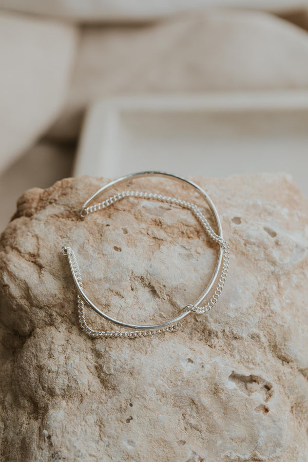 A silver cuff bracelet with a chain bracelet attached for an everyday jewelry piece created by Hello Adorn.