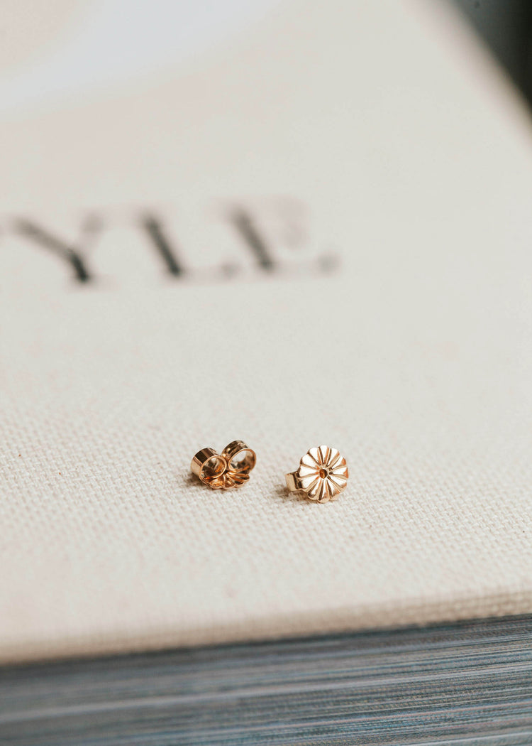Gold earring backs laying flat by Hello Adorn.