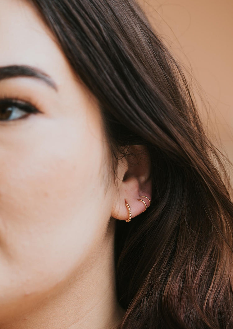 Simple gold earrings for daily use in beaded hoop earring style shown with a double up post used for creating a fake double piercing by Hello Adorn. 