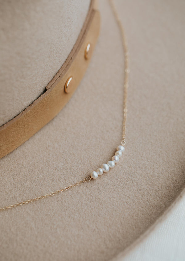 A pearl necklace from Hello Adorn, a dainty chain with pearls attached to create a statement necklace.