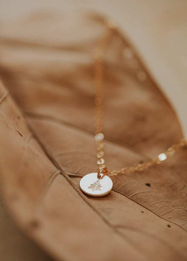 A custom necklace with a tiny circle charm hand-stamped with a symbol on a 14k gold fill chain necklace created by Hello Adorn.