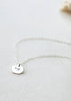 A silver custom necklace pendant created as a heart necklace that includes a symbol stamped on jewelry by Hello Adorn.