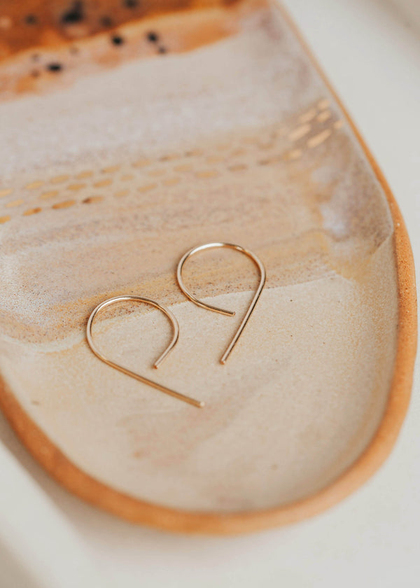 A pair of gold threader earrings handmade by Hello Adorn from wire earrings that look like the letter p or half hoop earrings.