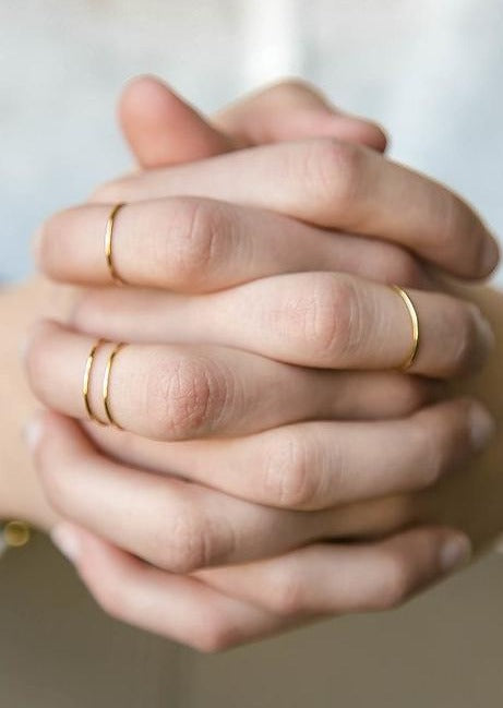 Four Teeny-Tiny Band in 14k Gold Fill by Hello Adorn stacking rings shown styled on hands.