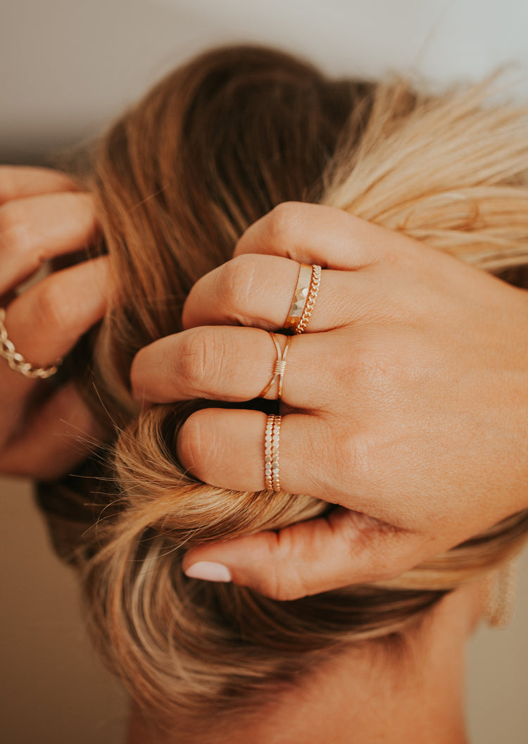 Stackable ring ideas by Hello Adorn, this stack features two hammered rings, a wire wrapped ring, a statement ring as a textured ring, and a gold chain ring.