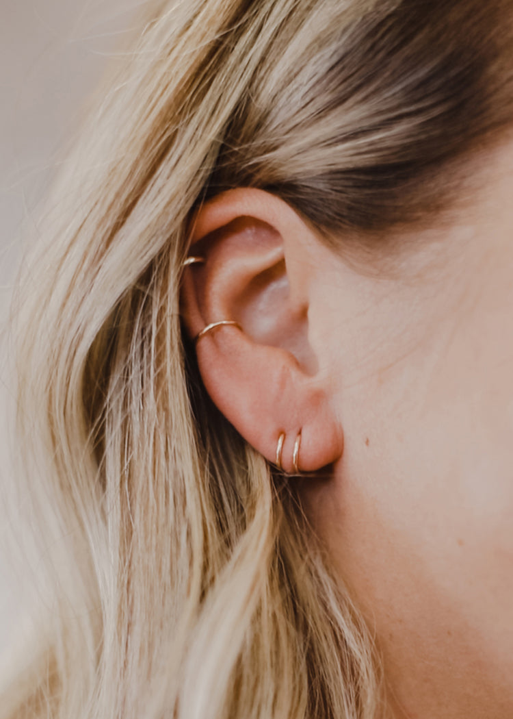Twist Earrings shown in an ear paired with Tiny Hoops.