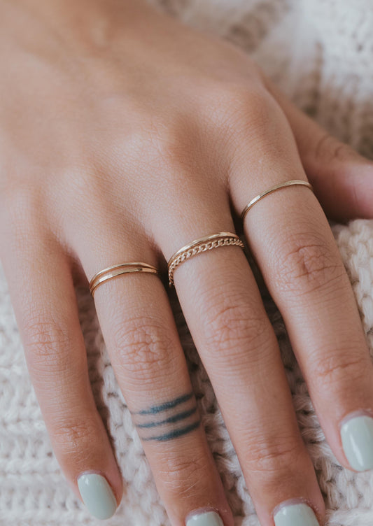 Learn how to stack rings on fingers with Hello Adorn with this 14k gold fill ring stack using two thin hammered rings, two thin ring bands, and a chain ring shown on a model.