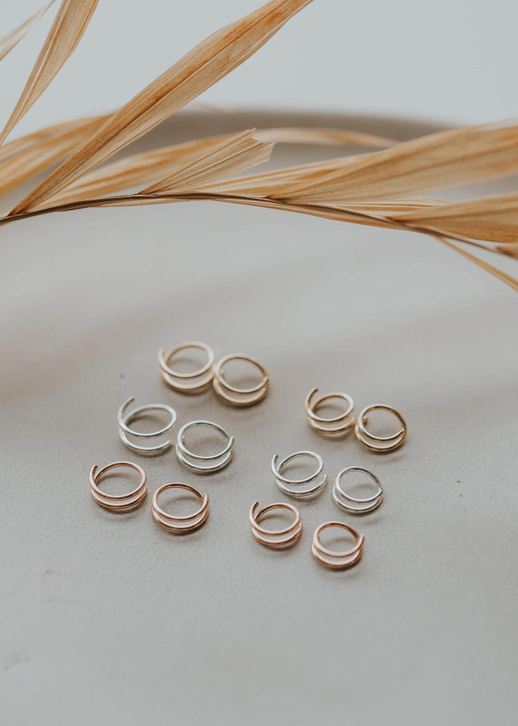 Tiny Twist Earrings in sterling silver, 14k gold fill, and rose gold laying flat by Hello Adorn.