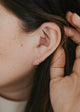 Twist Earrings being shown in an ear by Hello Adorn.