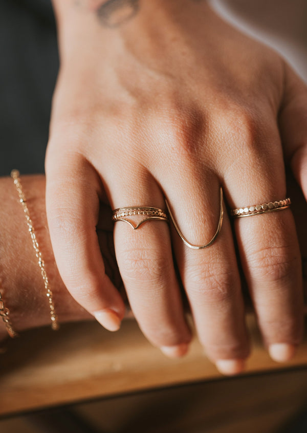 Ring stack idea created by Hello Adorn with valley trio which comes in a ring set of 3 with a thin ring, gold textured ring, and a curved ring styled with a statement ring in the swell ring style, another thin ring, a beaded ring, and permanent bracelet.