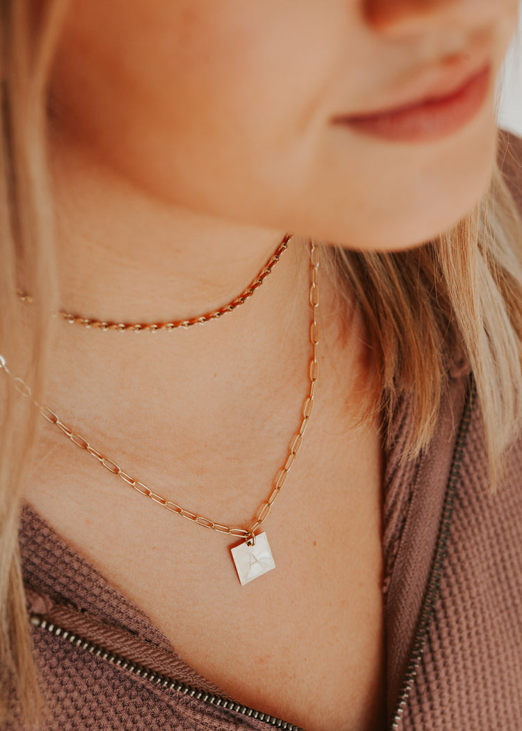 A 14kt Gold Fill chain link square initial pendant necklace layered with a gold choker chain.