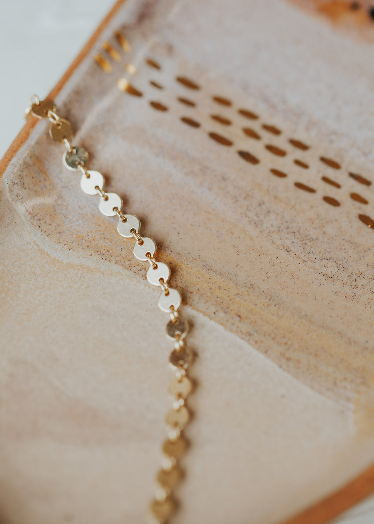 A 14kt Gold Fill clasp bracelet with round discs linked together.