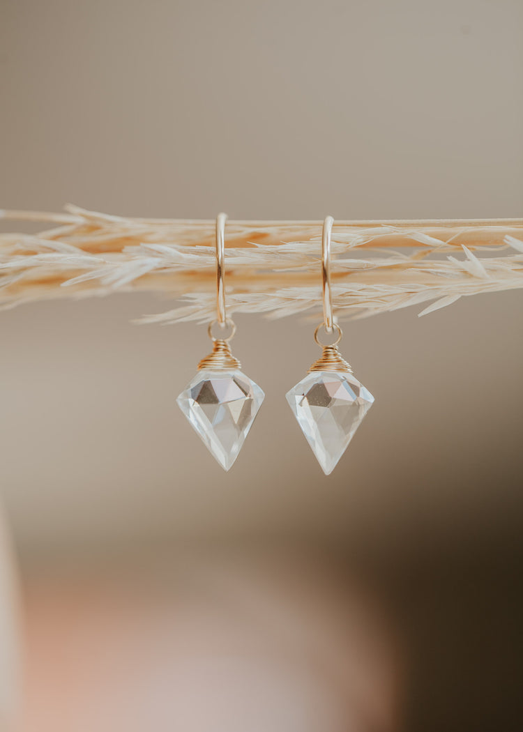 A dagger-shaped, faceted, crystal quartz stone is wire-wrapped and attached to a 14kt Gold Fill endless hoop earring. 