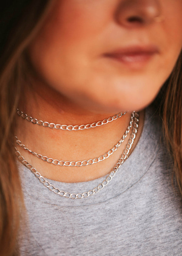 A young model layering bold curb chain necklaces in Sterling Silver.