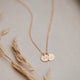 A custom necklace with a charm stamped with your personalized design by Hello Adorn to create a stamped necklace shown in 14k gold fill.