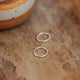Sterling silver hoop earrings laying flat on a table by Hello Adorn.