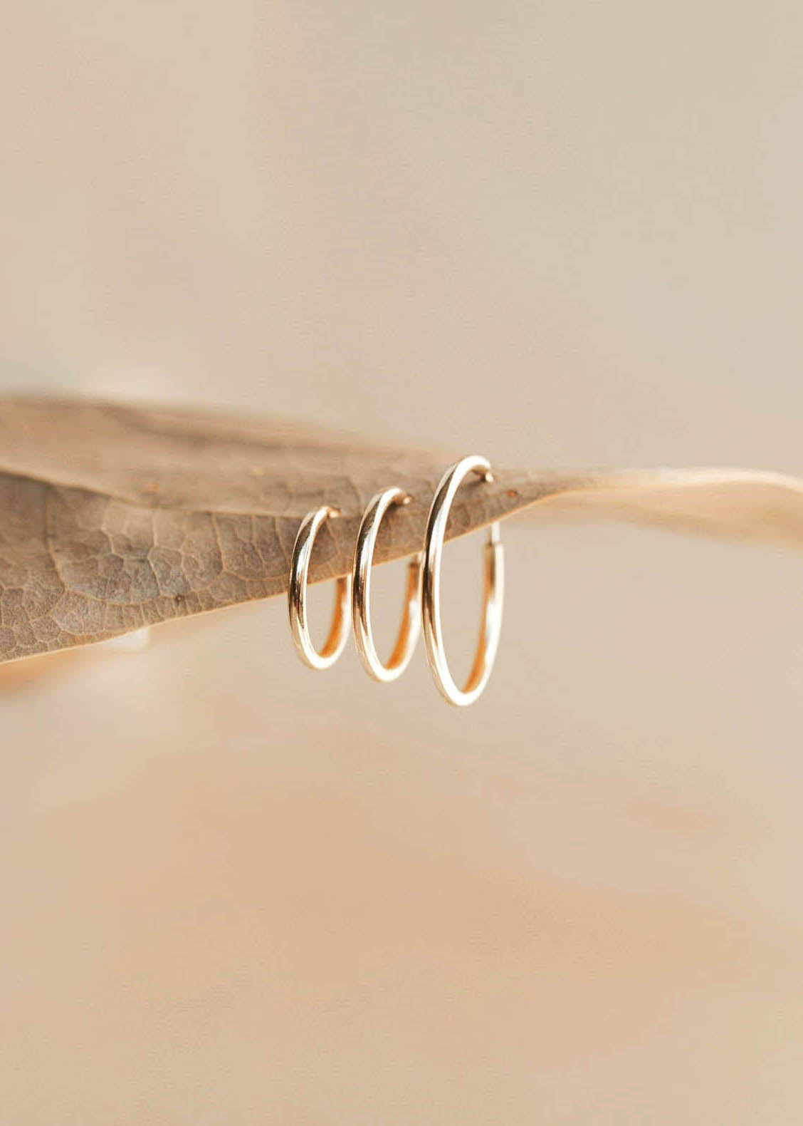 Gold infinity hoop earrings by Hello Adorn showing three difference sizes.
