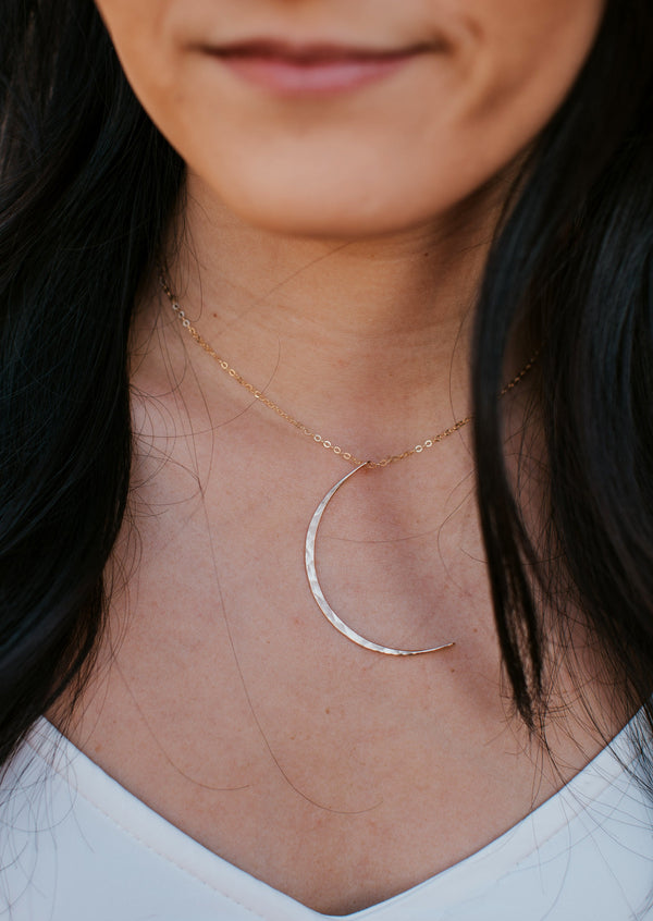 A model wearing a crescent moon necklace in 14k gold fill handmade by Hello Adorn.