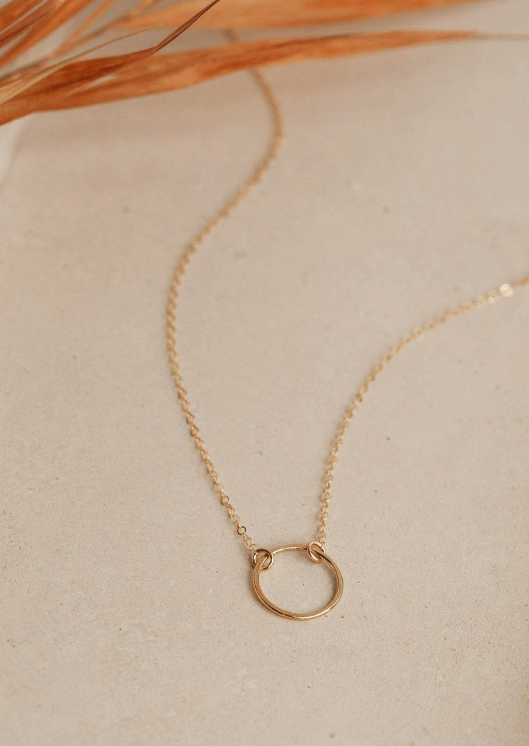 A necklace of circles with a circle pendant attached to a simple gold chain necklace handmade from Hello Adorn in the Full Circle Necklace design.