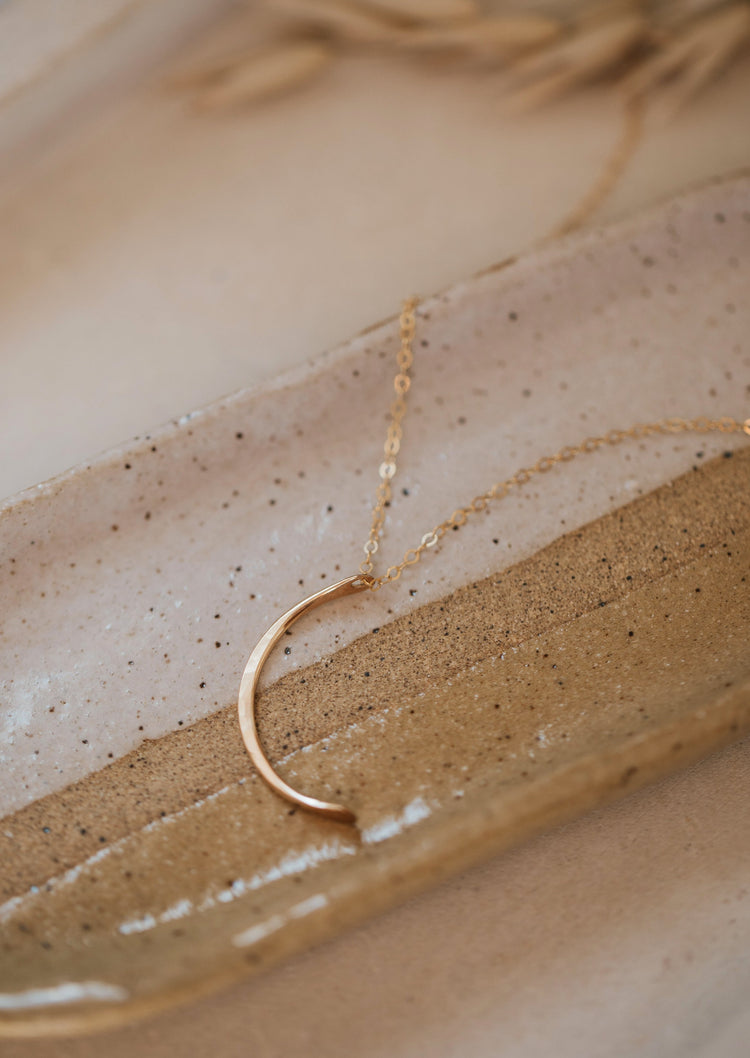 The mini-moon pendant necklace handmade by Hello Adorn made with a crescent moon pendant attached to a chain necklace, create a statement necklace to add to your necklace layering styles.