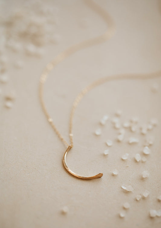 A crescent moon pendant attached to a dainty chain necklace created by Hello Adorn, this mini-moon necklace is perfect to finish a necklace layering look.
