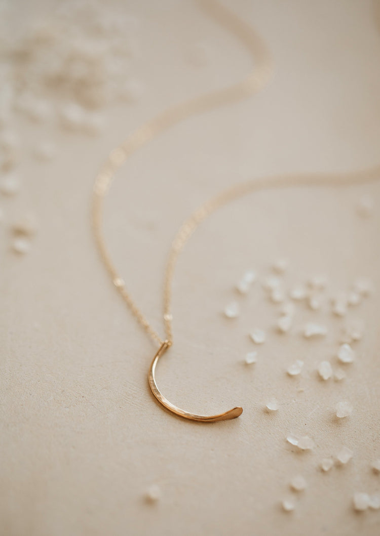 A crescent moon pendant attached to a dainty chain necklace created by Hello Adorn, this mini-moon necklace is perfect to finish a necklace layering look.