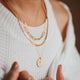 A necklace layering idea featuring a paperclip necklace linked to a dainty chain necklace paired with a necklace with flower and a thick layering chain necklace handmade by Hello Adorn.