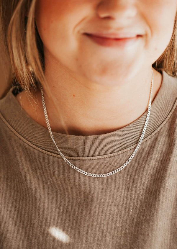 Genderless flat curb chain necklace on a young female.