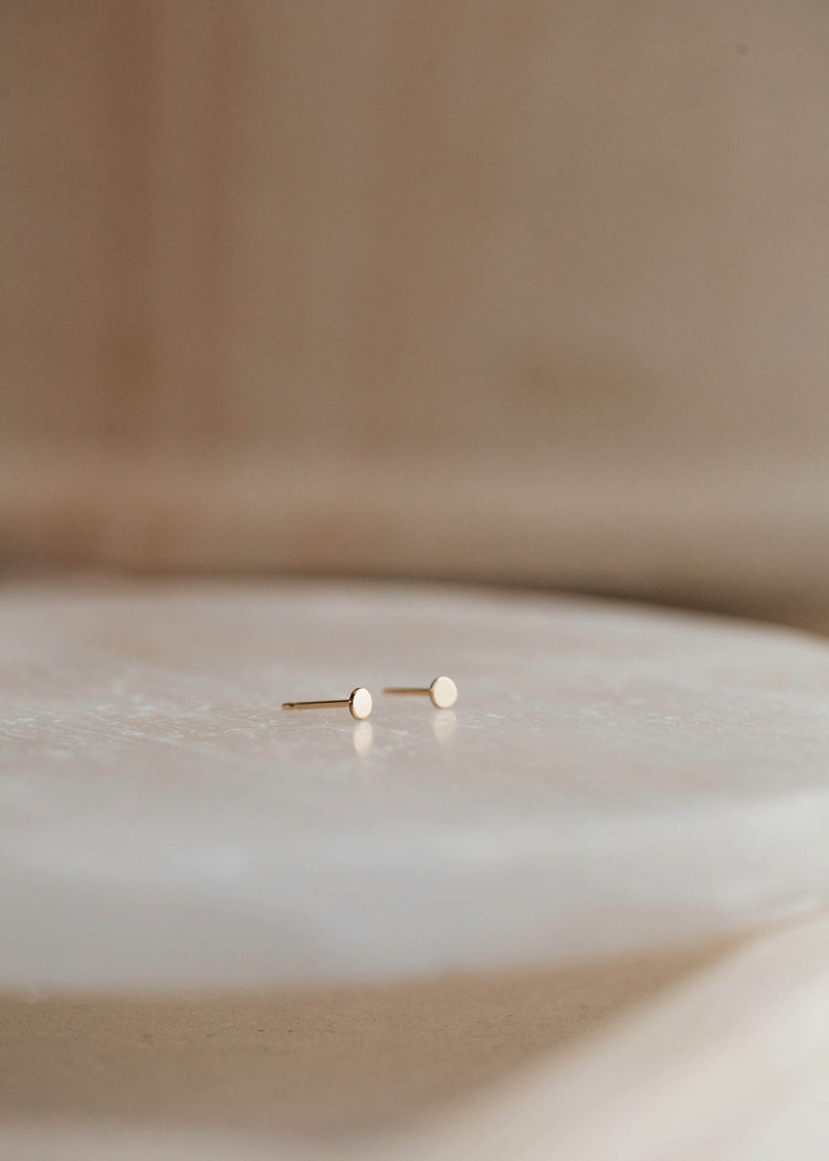 14k gold fill tiny dot studs by Hello Adorn laying flat.