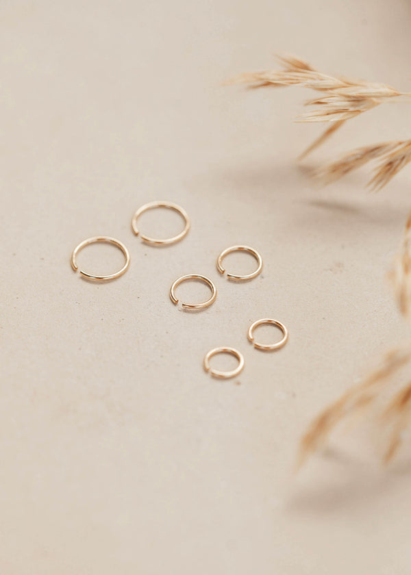 Gold hoop earring shown in three different sizes in 14k gold fill laying flat by Hello Adorn.