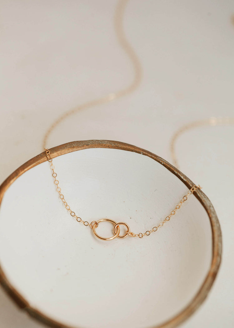 14k gold fill interlocking circle necklace by Hello Adorn laying flat in a jewelry tray.