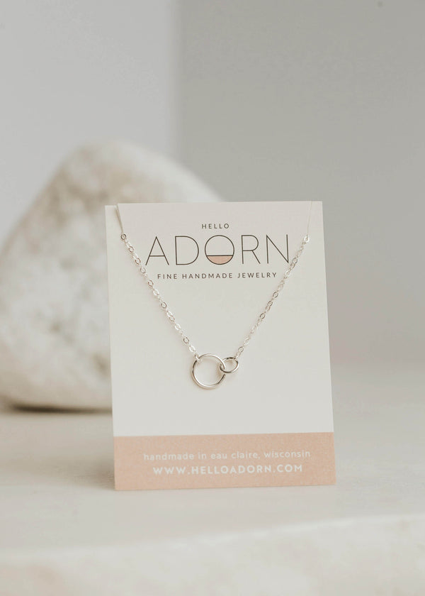 Sterling silver interlocking circle necklace shown on a Hello Adorn jewelry card.