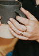 A model wearing a gold ring stack with handmade rings from Hello Adorn in a chain ring style, two thin rings, and a wire wrapped ring in the Triple Wrap Ring design.