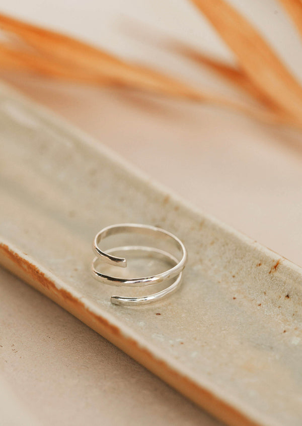 A silver statement ring that looks like 2 rings, but is only one wire wrapped ring using thicker wire to create the Wrap Ring by Hello Adorn.